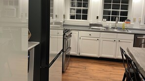 Eine moderne Küche mit weißen Schränken, einem Edelstahlkühlschrank und Holzboden.