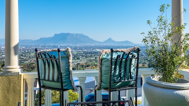 Two chairs with fur-edged cushions, a potted plant, and a view of a mountain range. - Cape Grandeur (Cape Town)