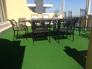 A rooftop terrace with a green artificial turf, a metal table, and matching chairs. - Cape Grandeur (Cape Town)