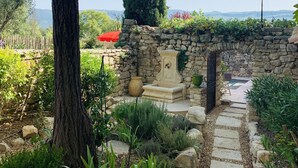A stone pathway leading to a stone wall with a gate, surrounded by greenery and a view of distant hills. - House with Provencal charm for lovers of authenticity. (Saignon)