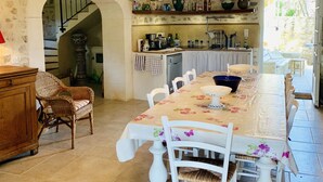 A spacious dining area with a long table, white chairs, and a chandelier. - House with Provencal charm for lovers of authenticity. (Saignon)