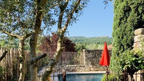 A stone gate leading to a pool area with a view of a hill and a castle in the distance. - House with Provencal charm for lovers of authenticity. (Saignon)
