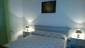 Une chambre à coucher avec un lit, deux tables de chevet et une petite table d’appoint.