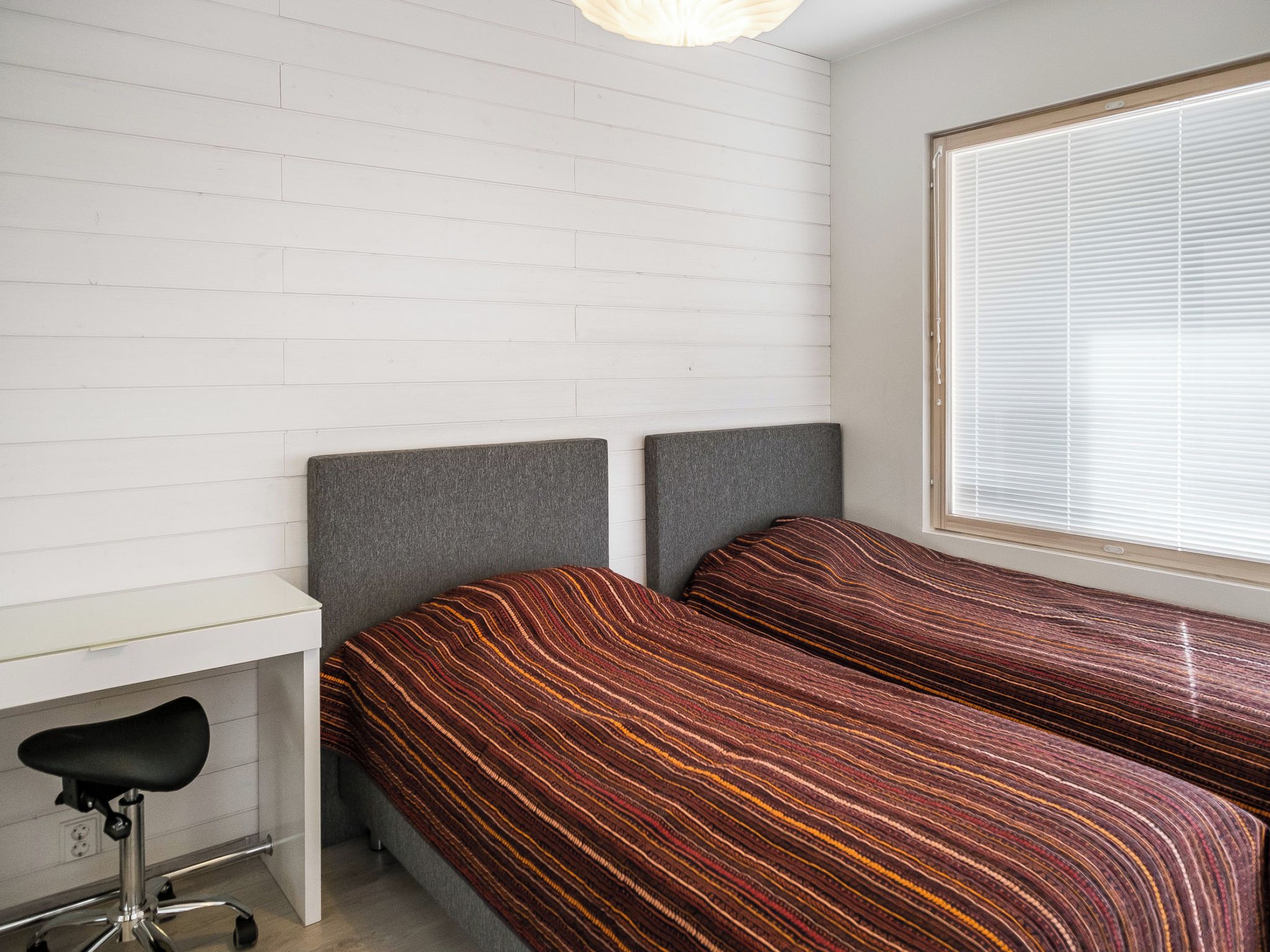 A bedroom with two beds, a desk, and a chair.