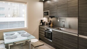A modern kitchen with a built-in microwave, stainless steel appliances, and a glass dining table with placemats.