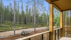 A wooden deck with a view of a forested area and a gravel path.