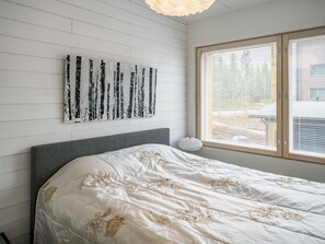 A bedroom with a bed, a wall-mounted artwork, a window with blinds, and a bedside lamp.