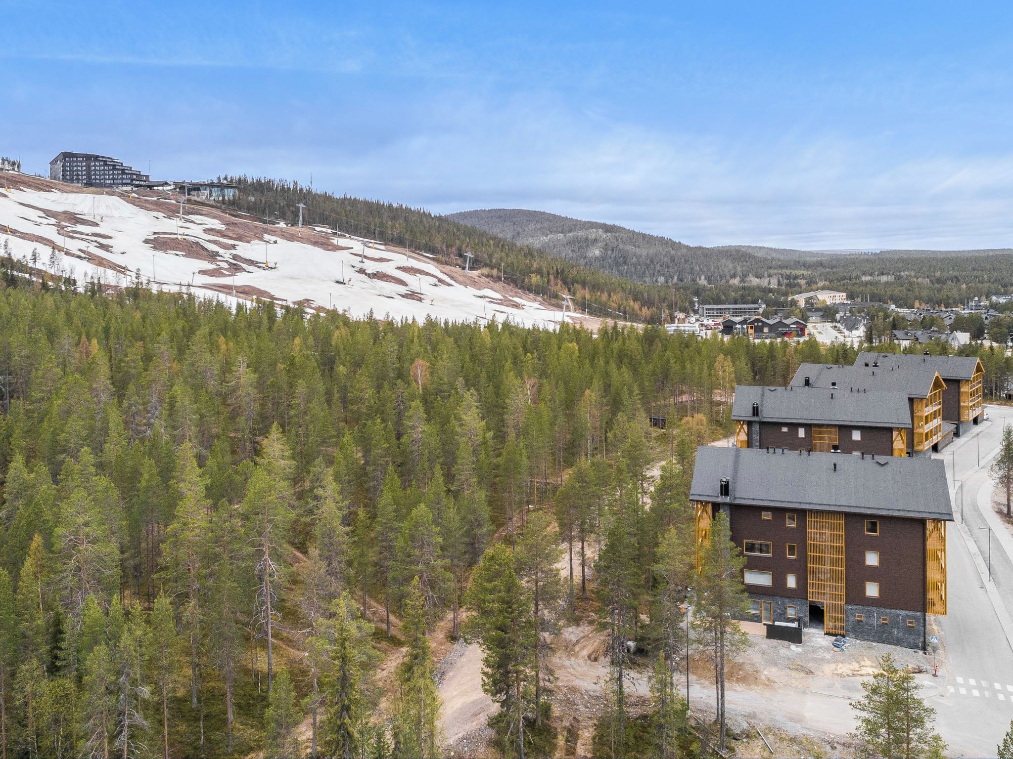 A multi-story building with a modern architectural design, surrounded by a dense forest and a snow-covered landscape.