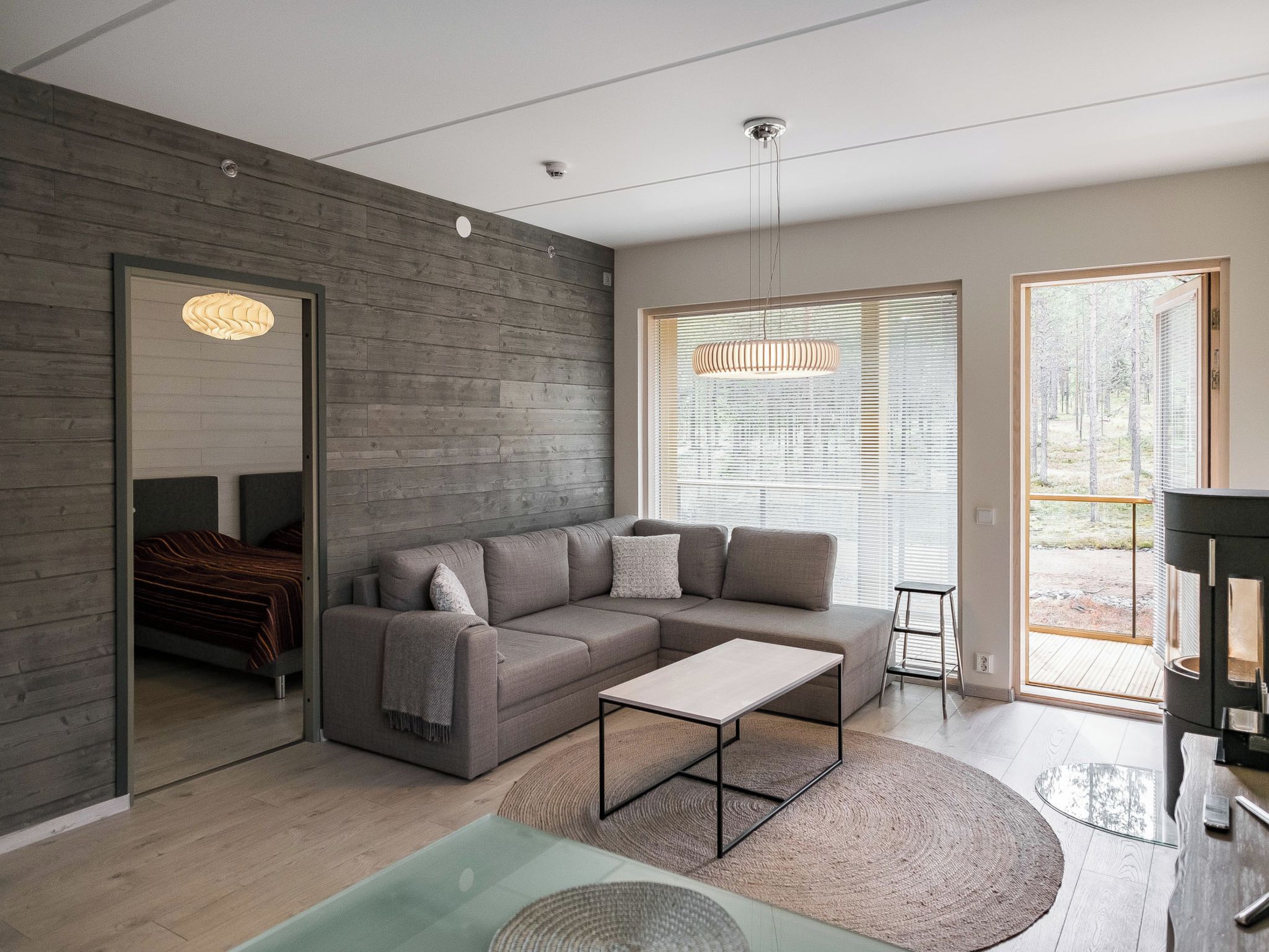 A modern living room with a sectional sofa, a coffee table, and a large window with blinds.