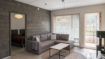 A modern living room with a sectional sofa, a coffee table, and a large window with blinds.