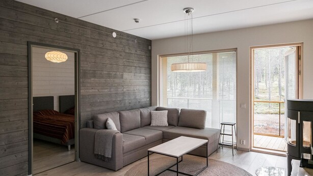 A modern living room with a sectional sofa, a glass coffee table, and a large window with blinds.