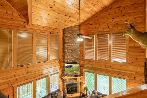 L’intérieur d’une cabane en rondins, avec une cheminée en pierre, des murs en bois et une tête de cerf accrochée au mur.