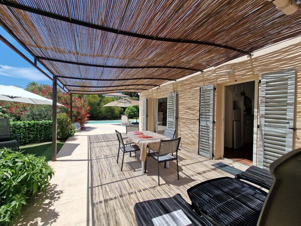 A covered patio area with a pool, outdoor furniture, and a view of the pool.