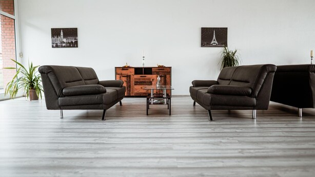 A modern living room with two leather armchairs, a wooden cabinet, and two framed pictures of famous landmarks. - Milde Hotel (Kalbe)
