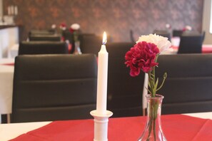 Una vela y un florero con flores sobre una mesa.