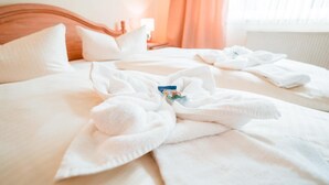 A hotel room with a neatly made bed, a wooden headboard, and a window with curtains. - Milde Hotel (Kalbe)