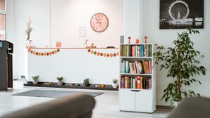 A modern living room with a bookshelf, a clock, and a framed picture on the wall. - Milde Hotel (Kalbe)