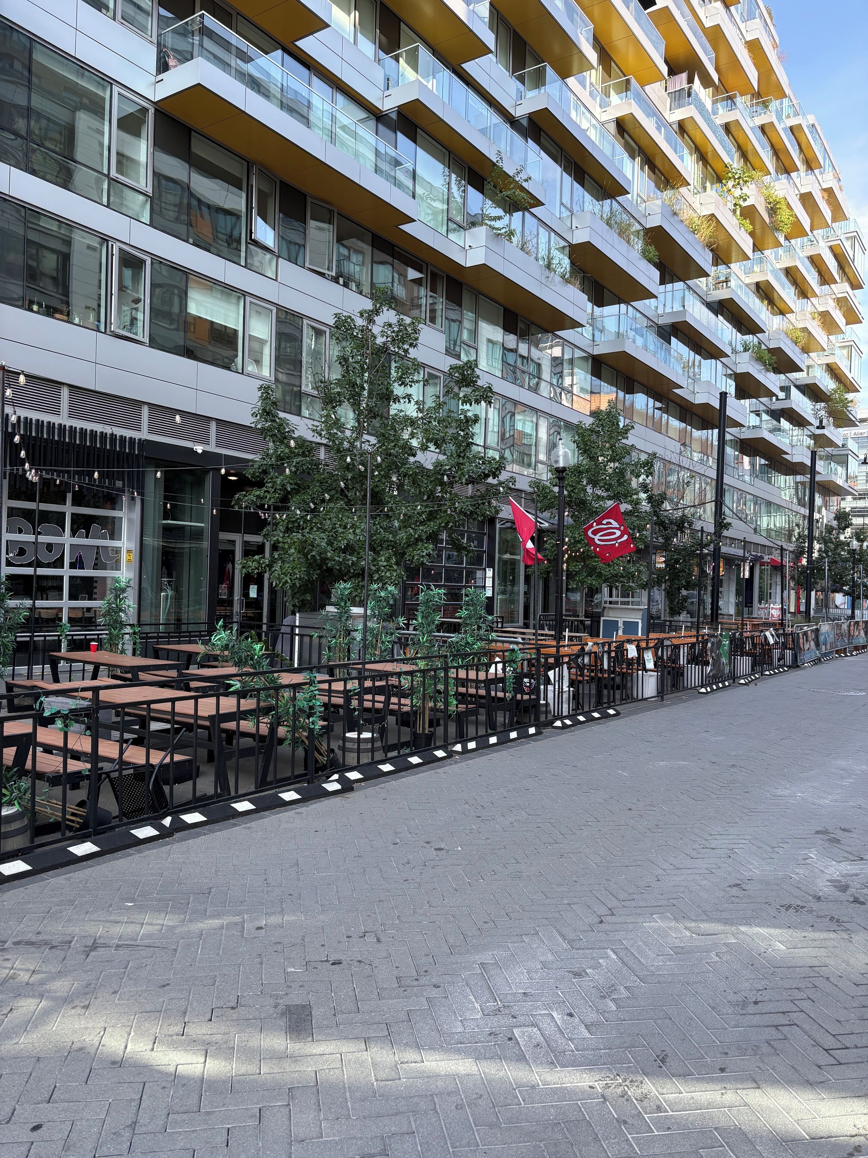 A modern building with multiple balconies, outdoor seating, and a clear sky.