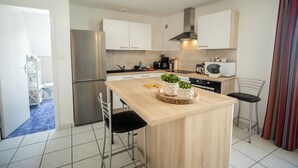 Une cuisine moderne avec des meubles blancs, un réfrigérateur en acier inoxydable, une machine à café et un four à micro-ondes.