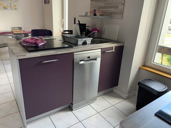 Una cocina compacta con lavavajillas, un lavabo y un ventanal.