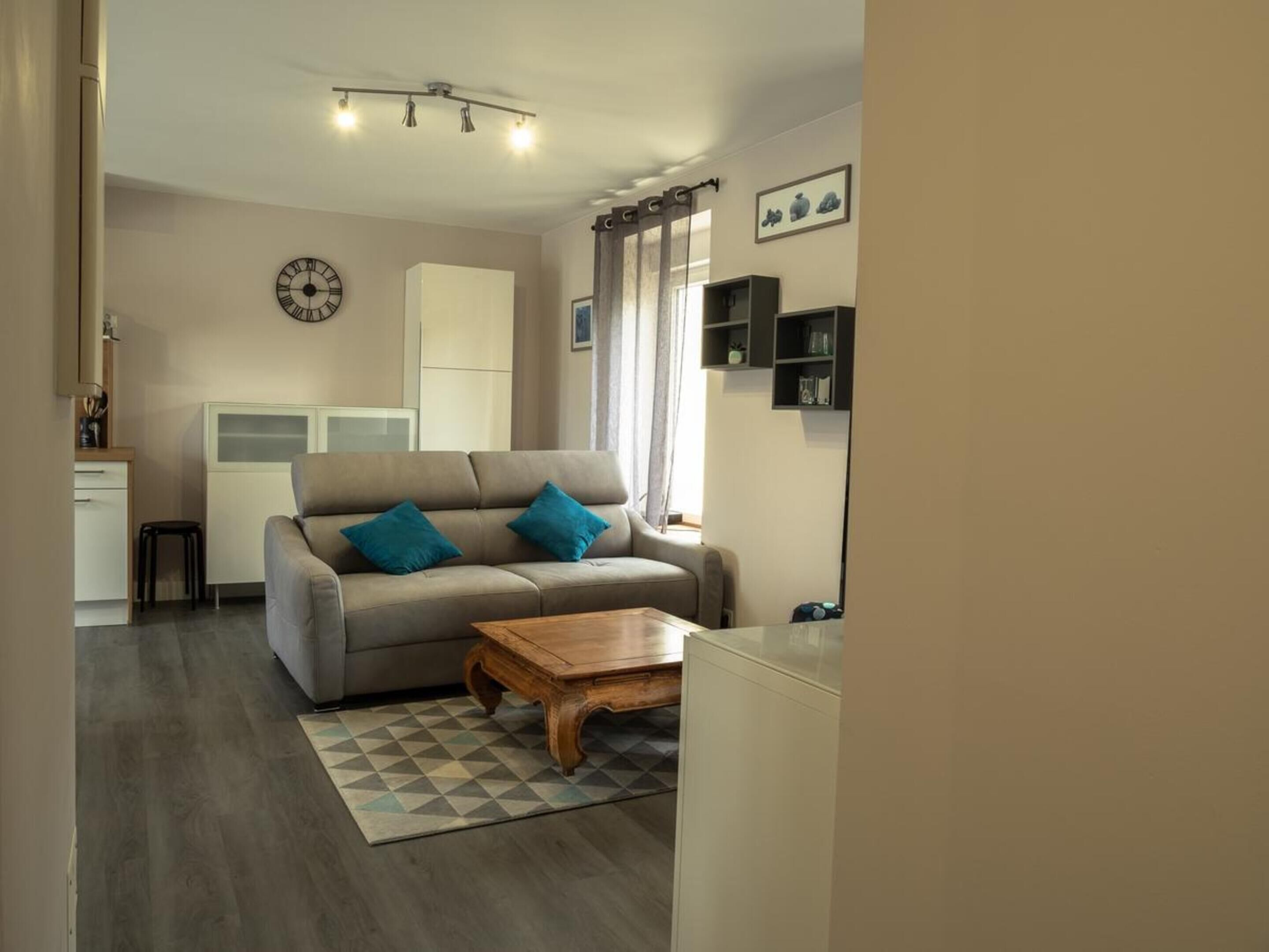 Un salon avec un canapé, une table basse et une horloge au mur.
