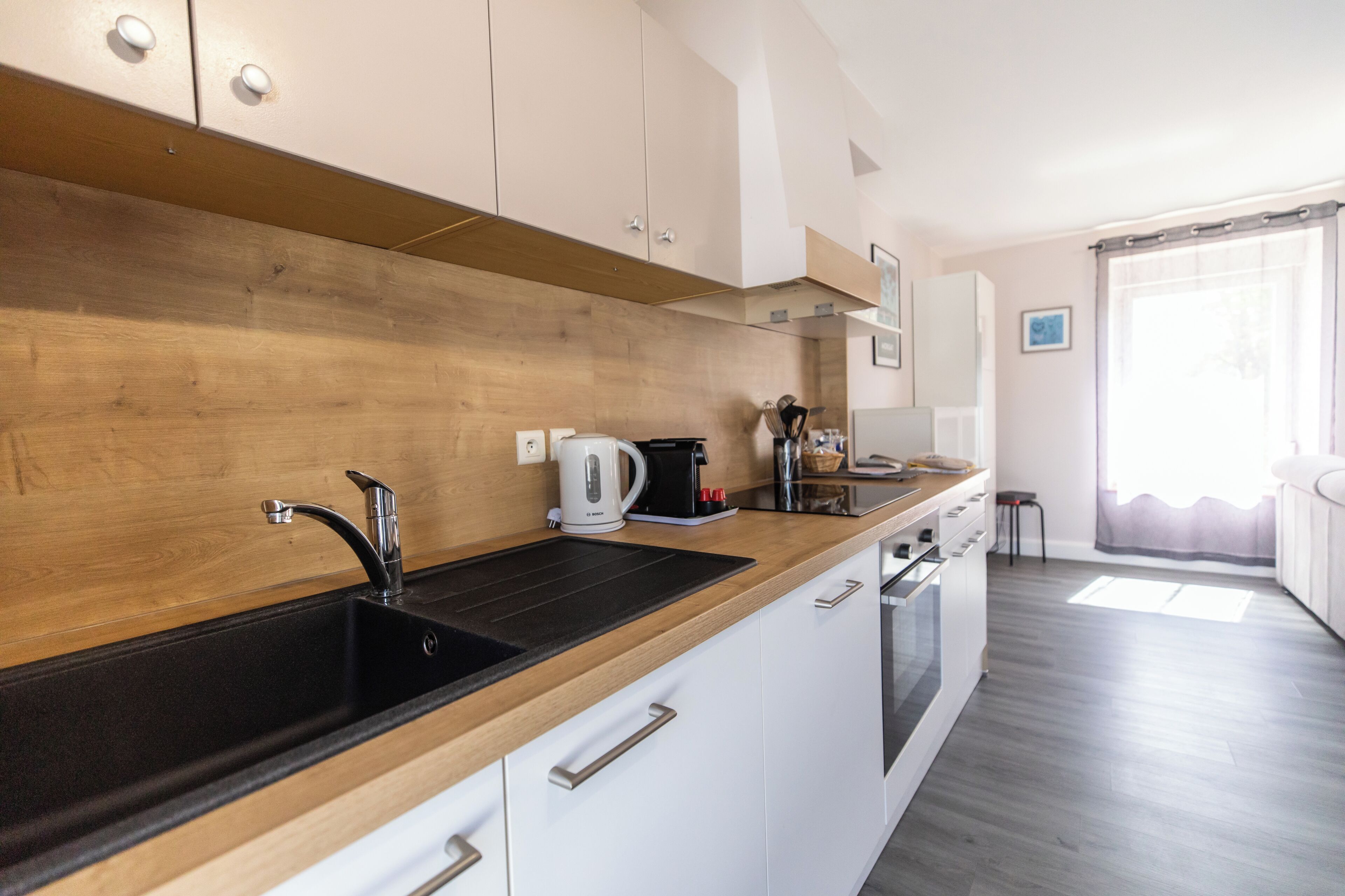 Une cuisine moderne dotée d’un plan de travail en bois, d’un évier en acier inoxydable et de meubles blancs.