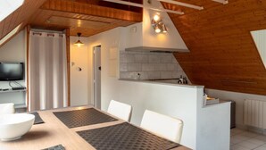 Une cuisine moderne avec un plafond en bois, une cuisinière intégrée et un petit îlot central.