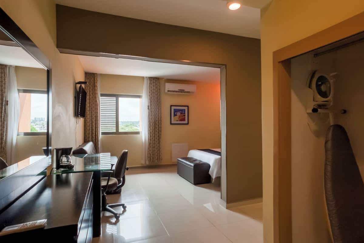 Quarto de hotel moderno com escrivaninha de vidro, sofá confortável, mesa pequena e poltrona de massagem.