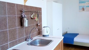 Une cuisine compacte équipée d’un évier, d’une cuisinière et d’un petit coin repas avec une nappe bleue.