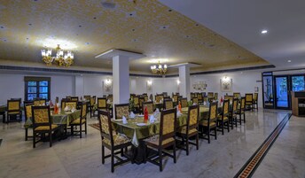 Un amplio comedor con numerosas mesas y sillas, candelabros y cuadros en las paredes.