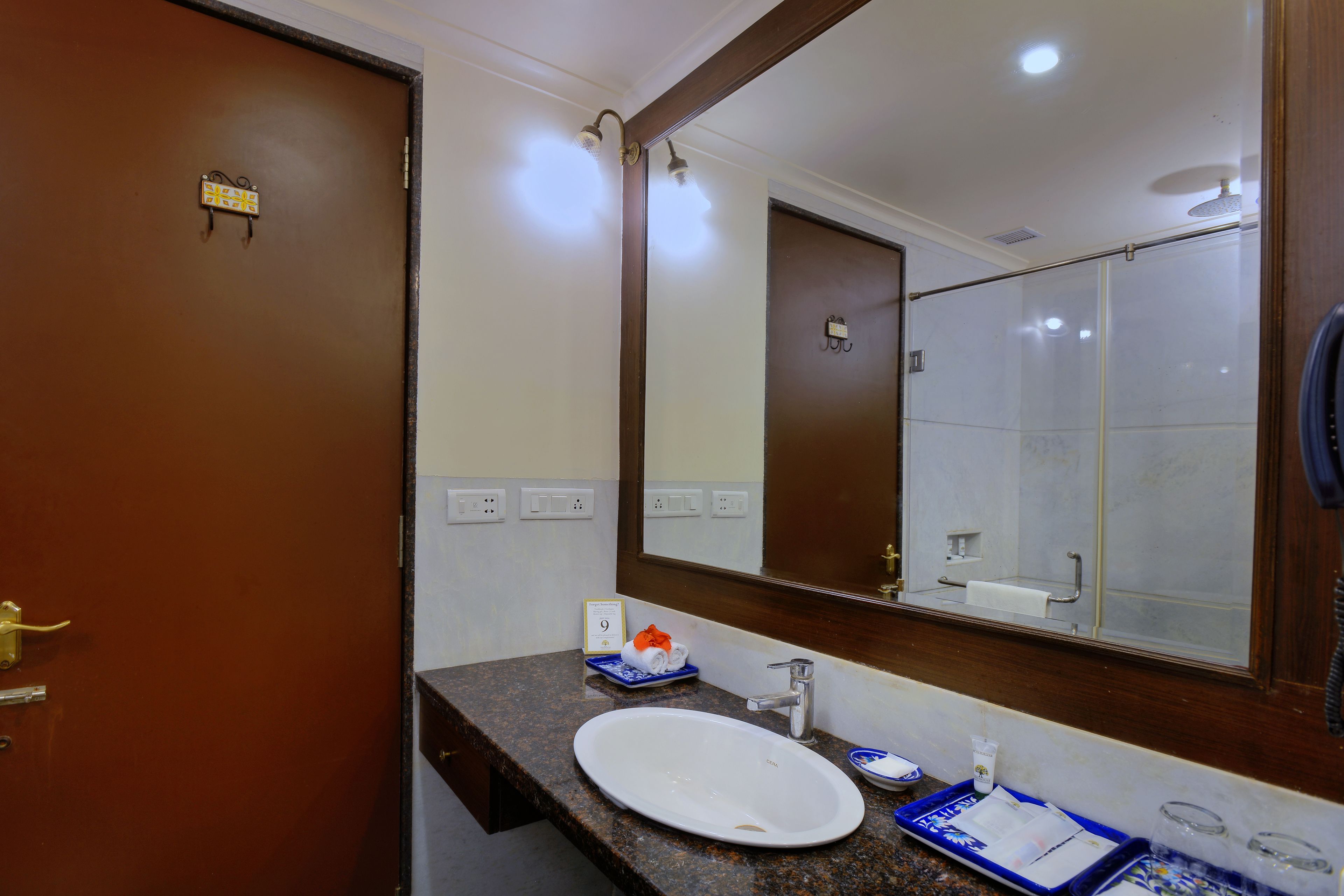 A hotel bathroom with a large mirror, a sink, a shower, and a towel rack.
