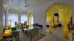 Una habitación bien iluminada con un sofá verde, una mesa de comedor y cortinas amarillas.