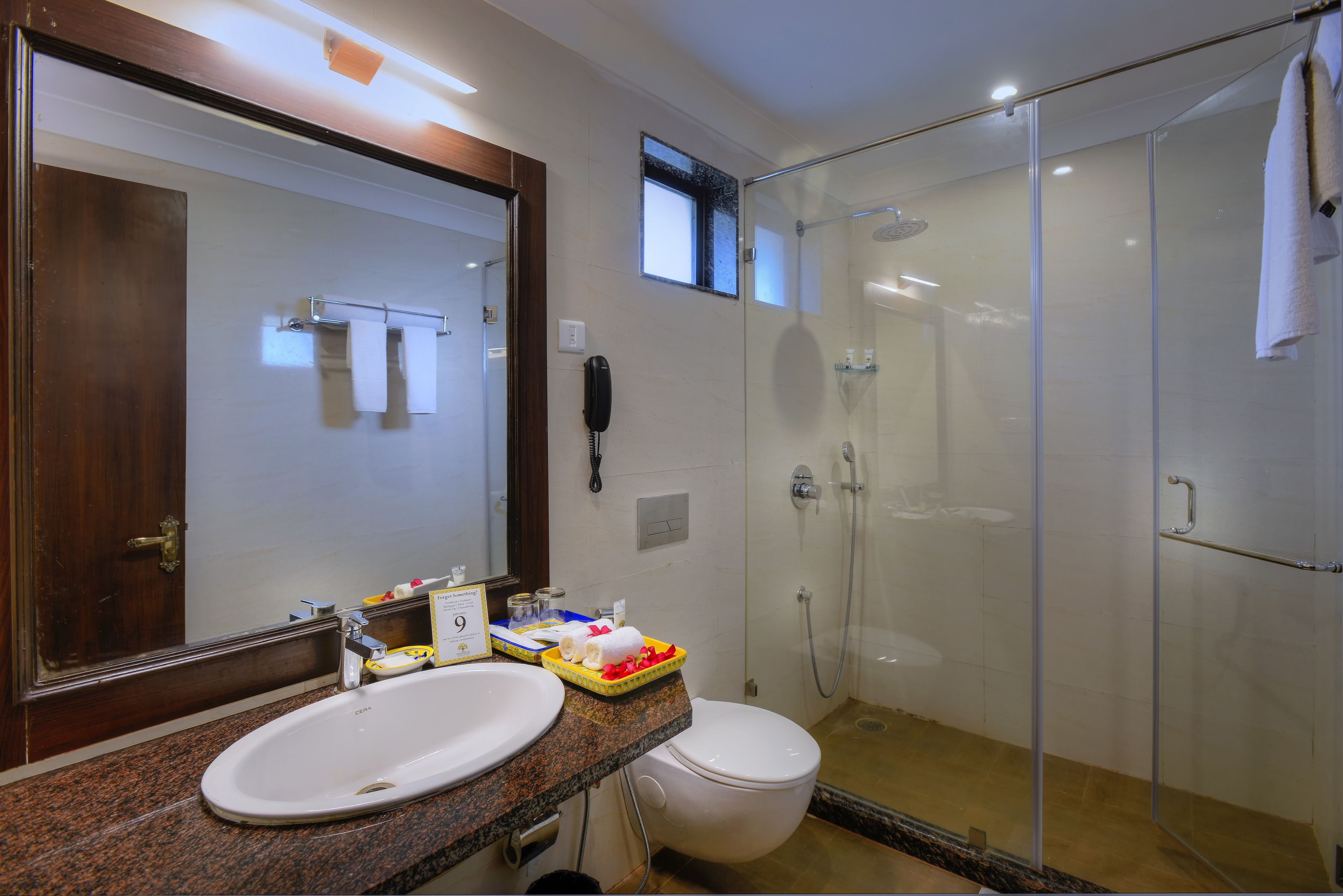 Un baño moderno con ducha envuelta en vidrio, tocador doble y un espejo grande.