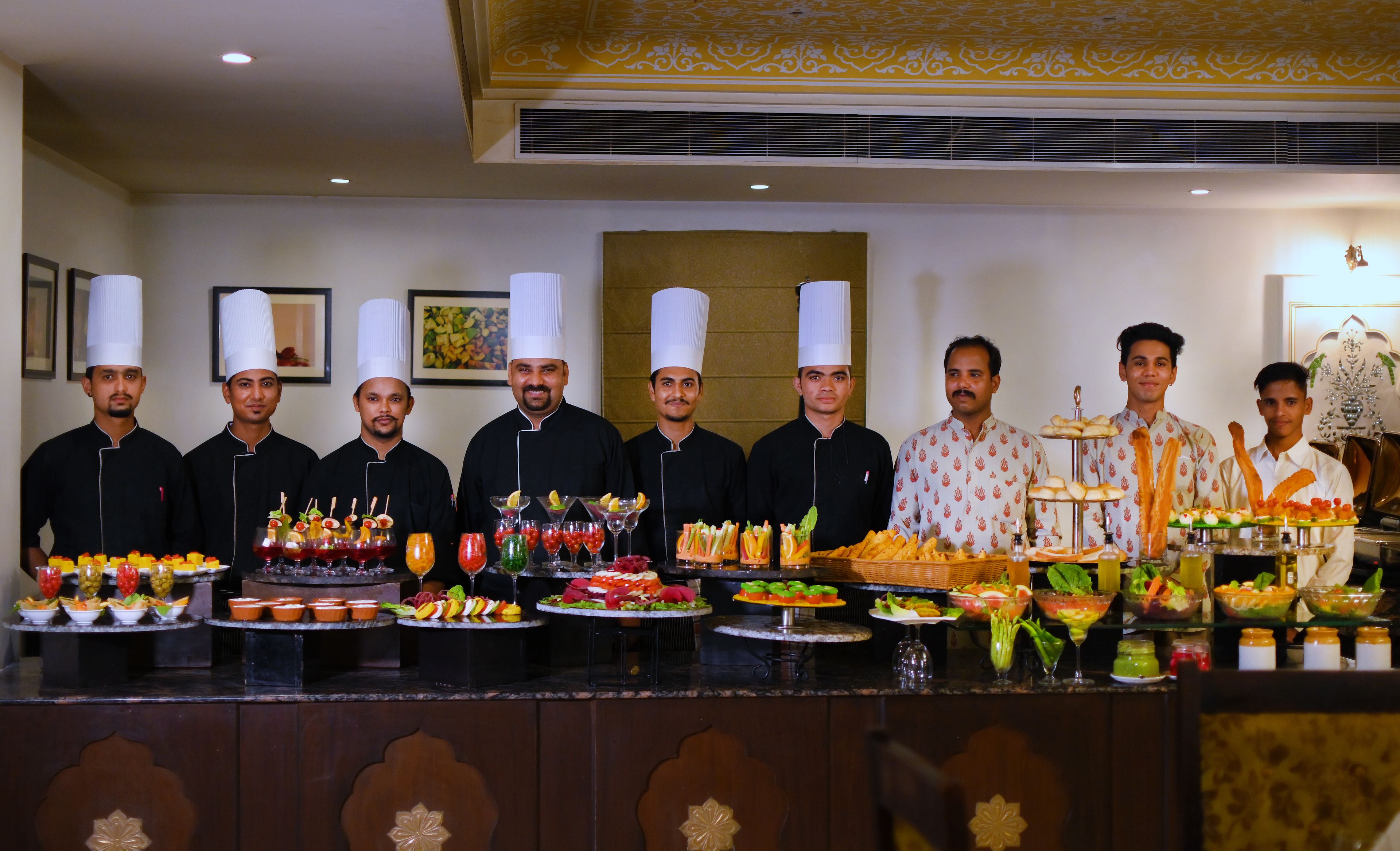 Un groupe de chefs se tient devant un buffet garni de divers plats et boissons.