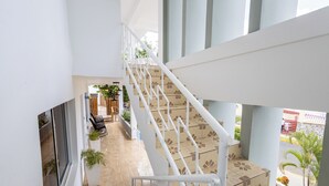 A multi-level interior with a central staircase, potted plants, and a seating area with chairs and tables. - Casa Docia Samana (Samaná)