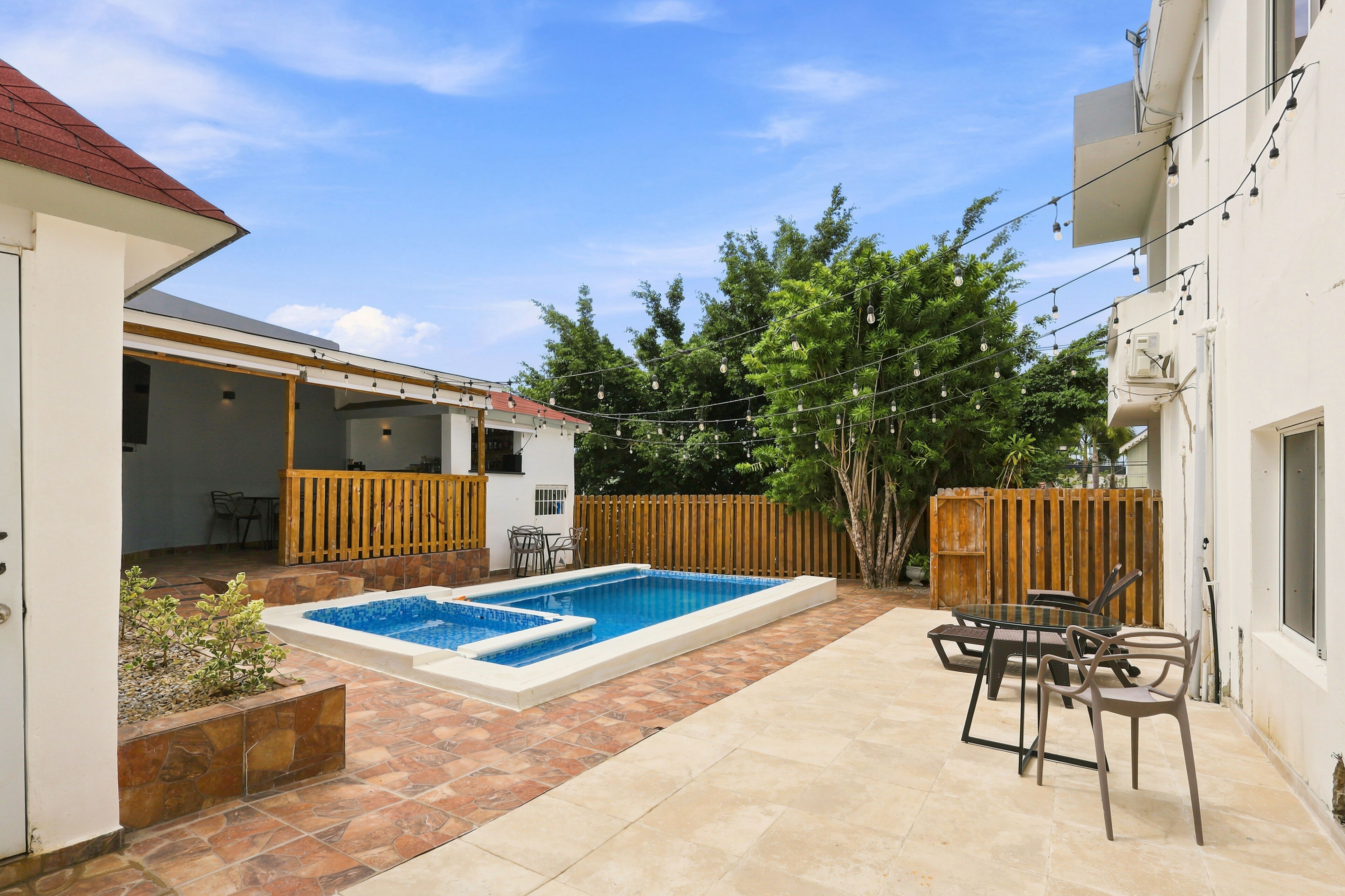 A backyard with a swimming pool, outdoor furniture, and a wooden fence.