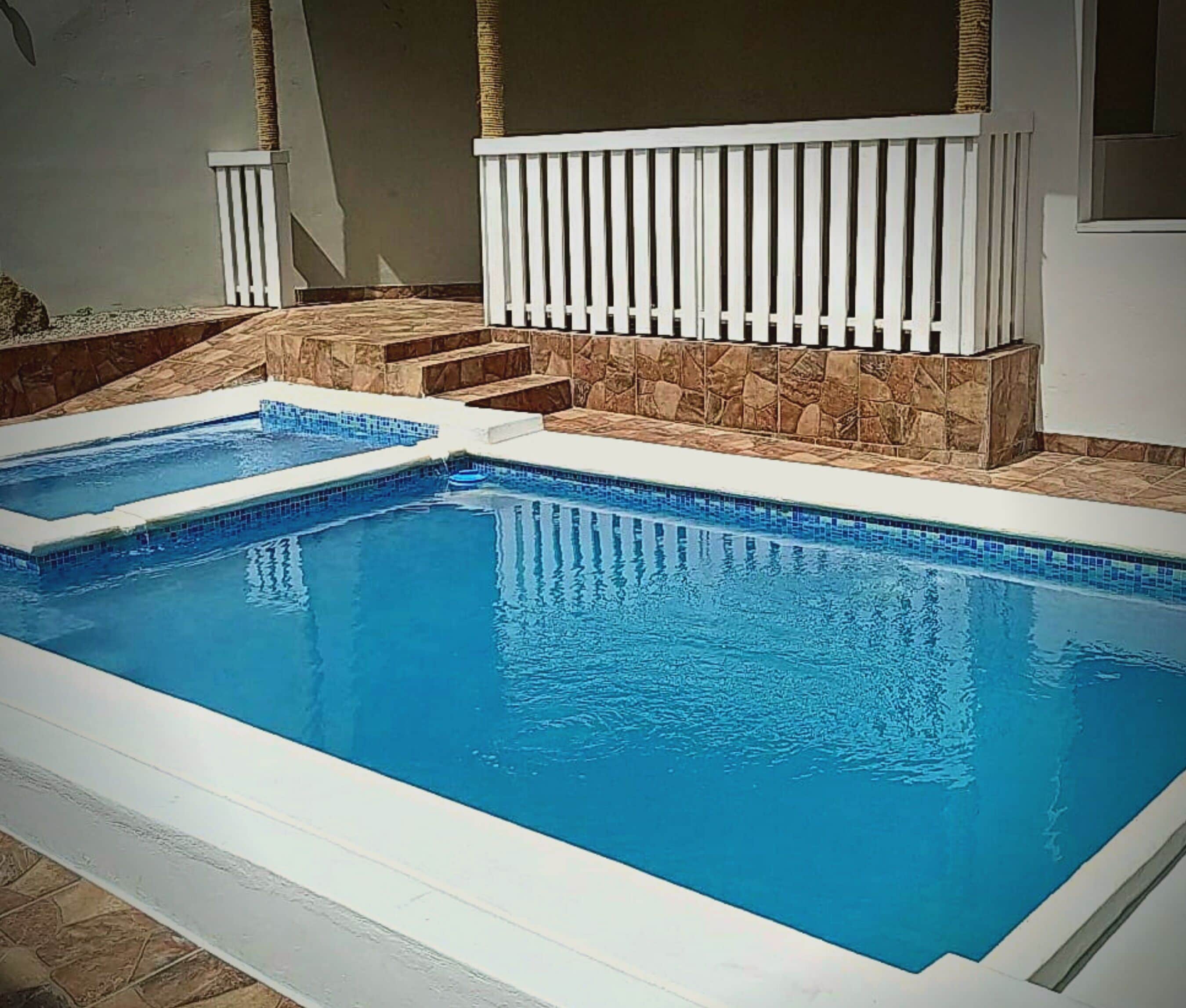 A rectangular swimming pool with a white deck and stone accents.