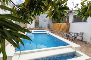 Una piscina al aire libre, sombrillas, sillones reclinables de piscina