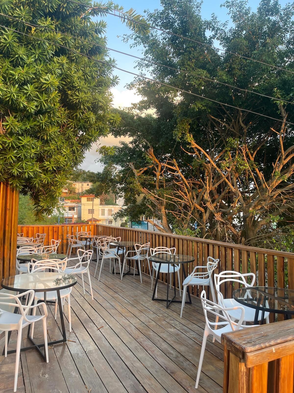 Une terrasse extérieure avec un sol en bois, des chaises et des tables en métal blanc.