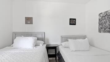 A twin room with two beds, a nightstand, and two wall decorations.