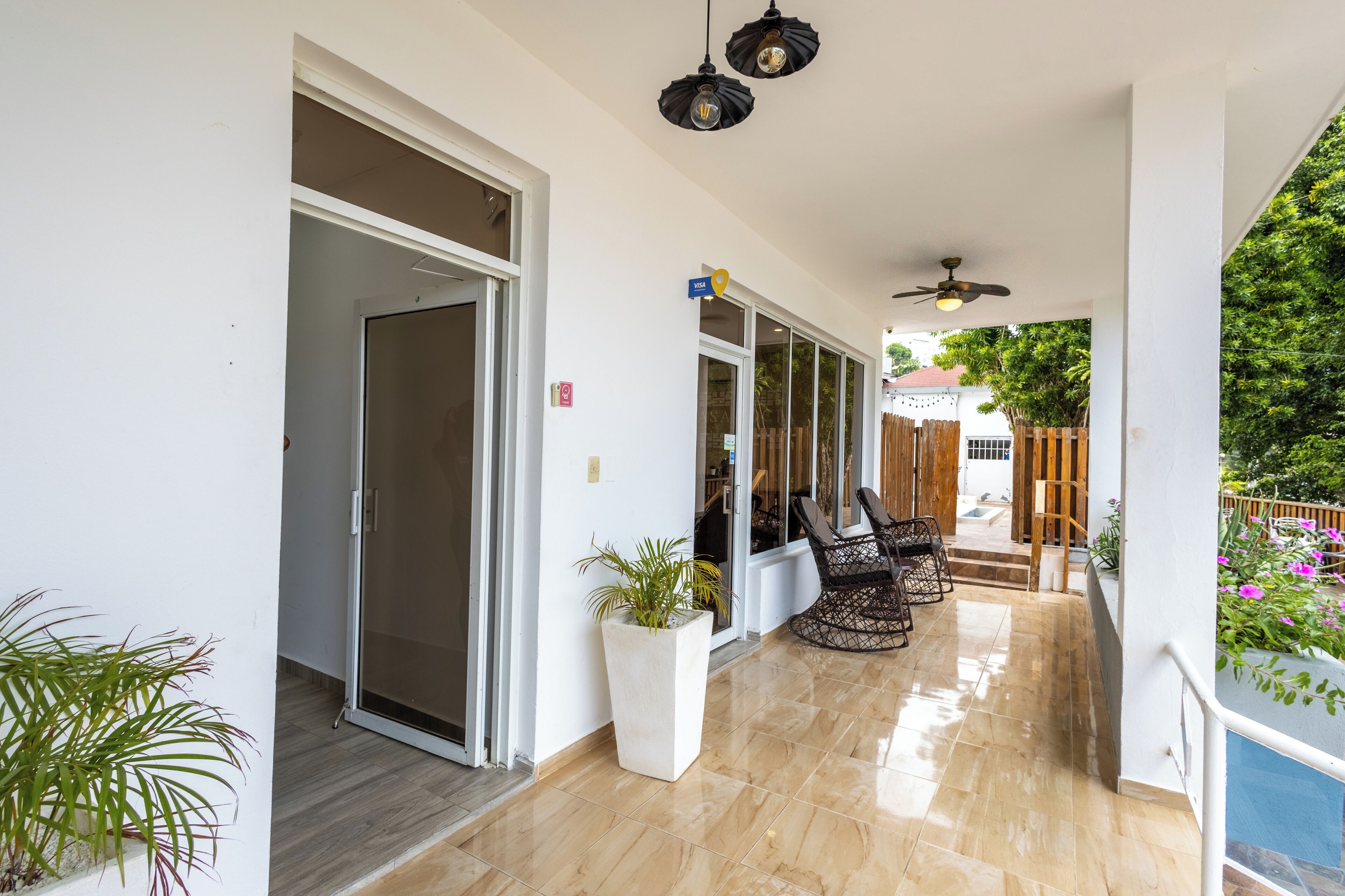 A covered outdoor area with a sliding glass door, a ceiling fan, and a seating area with chairs.