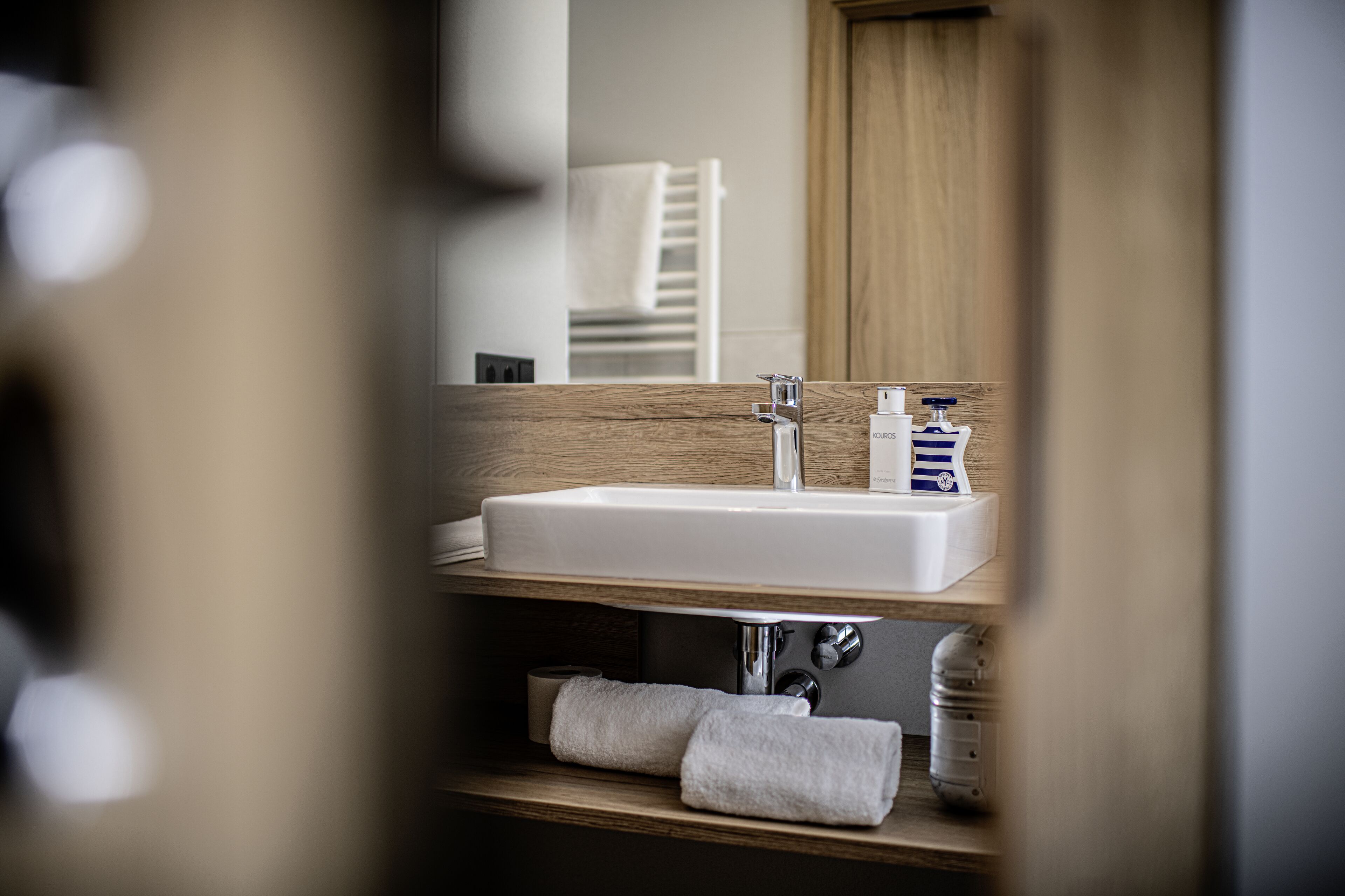 A bathroom with a wooden vanity, a white sink, and a mirror.