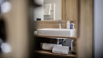 A bathroom with a wooden vanity, a white sink, and a mirror.