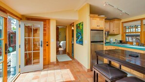 A kitchen with a central island, wooden cabinets, and a sliding glass door leading to a patio. - Stinson Beach Vibe - Easy Living w Garden & Outdoors Shower (Stinson Beach)