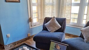 A room with a checkered sofa, a glass table with a brochure, and a window with curtains. - Apartamento El Duque (Córdoba)