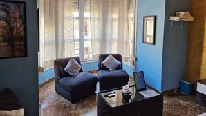 A room with two armchairs, a small table with a vase, and a framed picture on the wall. - Apartamento El Duque (Córdoba)