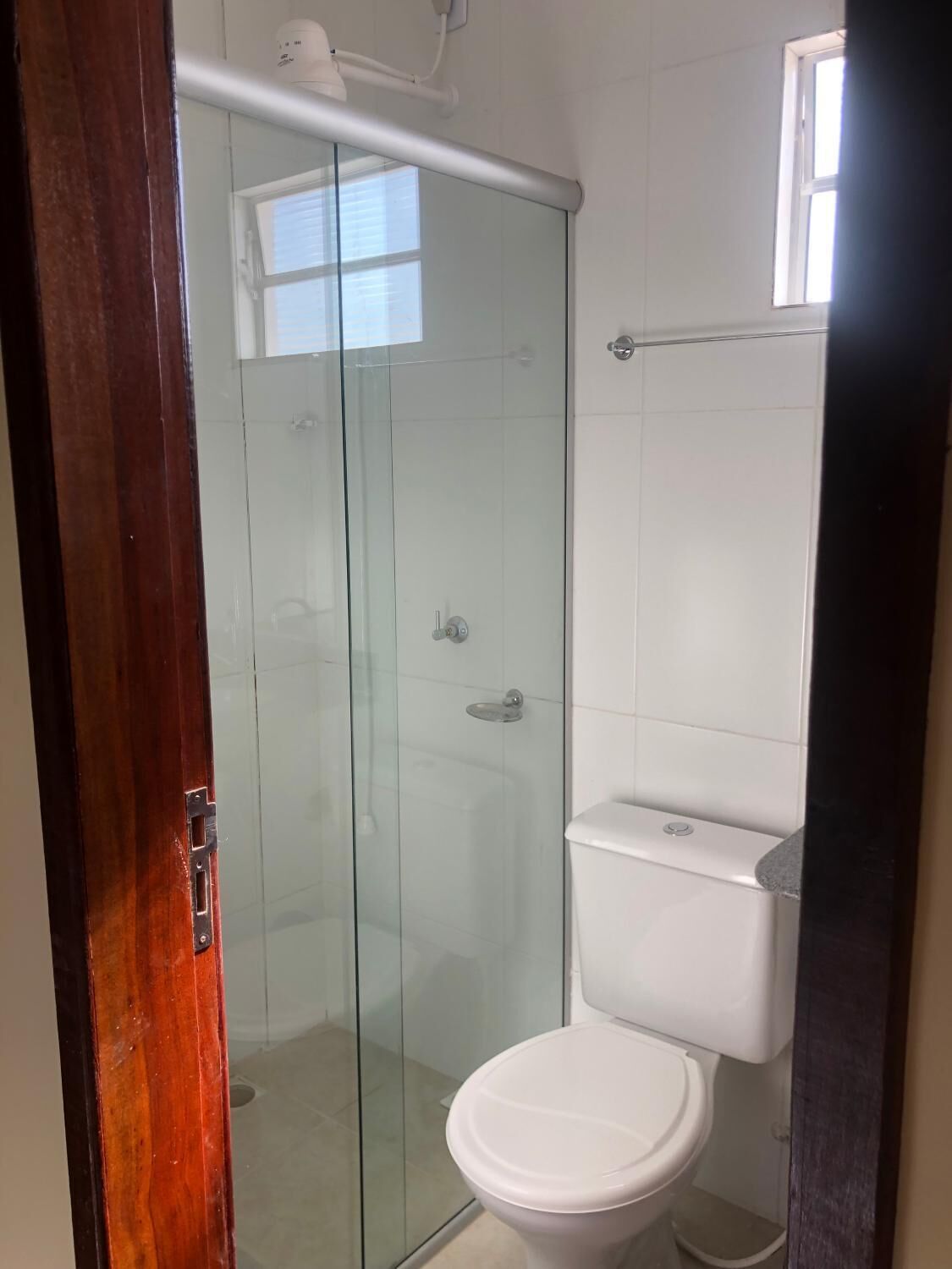 Un baño con cabina de ducha de vidrio, inodoro blanco y ventana que proporciona luz natural.