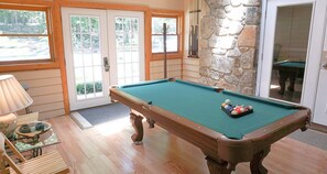 Enjoy a game of pool in this room with a pool table, door with glass panels, and comfortable seating.