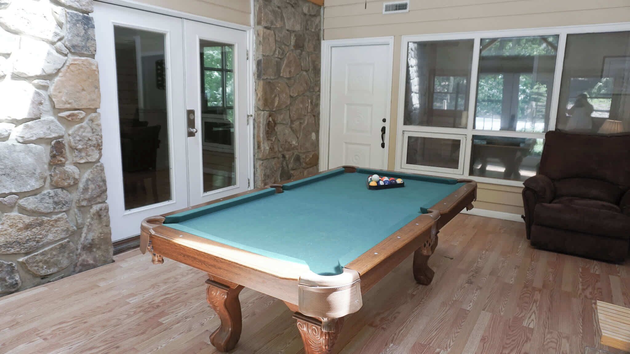 Una mesa de billar en una habitación con paredes de piedra y suelo de madera.