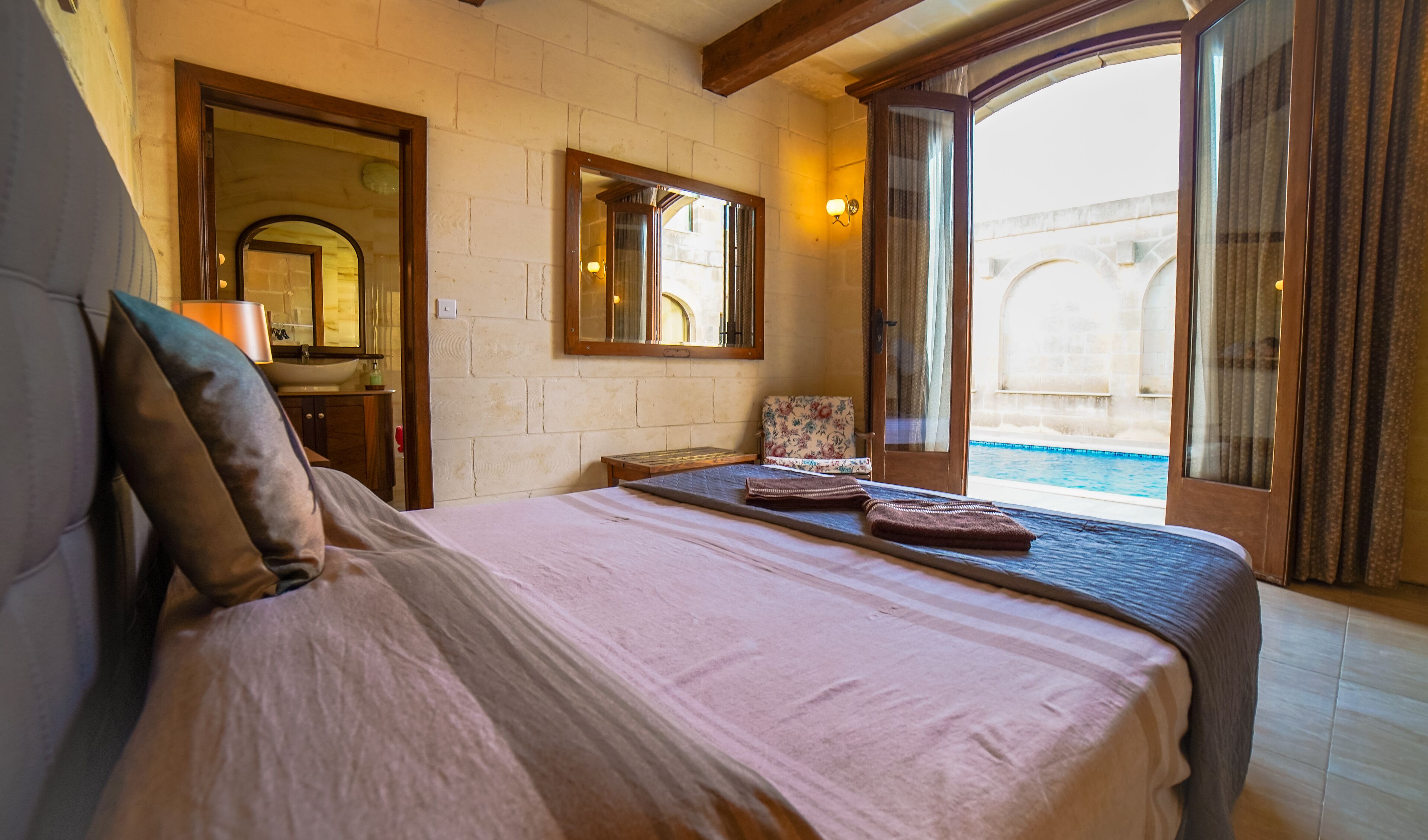 Une chambre avec un lit, une table de chevet, un miroir et une vue sur une piscine.